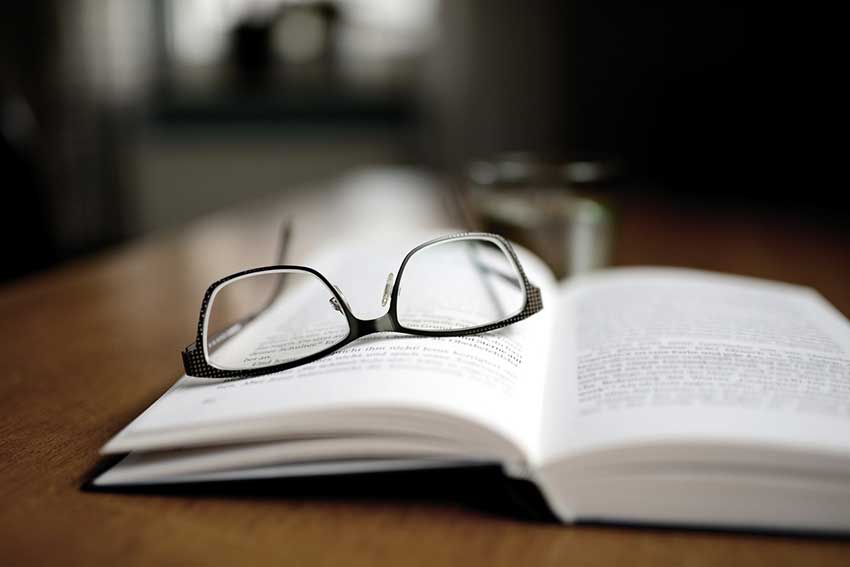 A pair of glasses laid across an open book